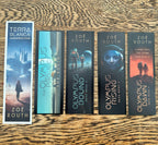 Five bookmarks from covers of the Zoe Routh and Terra Blanca author series arranged in a row on a wooden tabletop. The books include Insurrection, The Olympus Project, Olympus Bound, Olympus Rising, and Olympus Dawn.